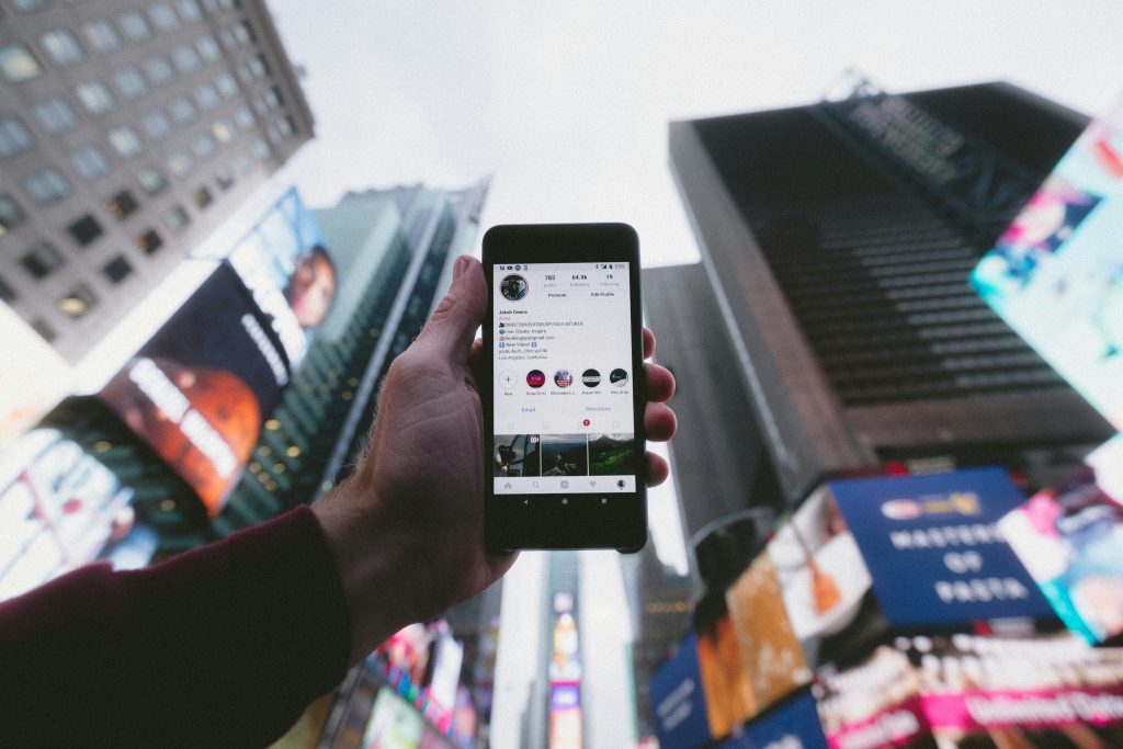 Man holding up phone with Instagram Profile onscreen